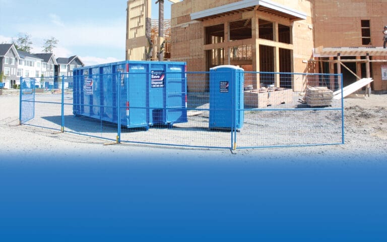 A construction site for a house build with a blue bin, blue portable toilet, and blue fence