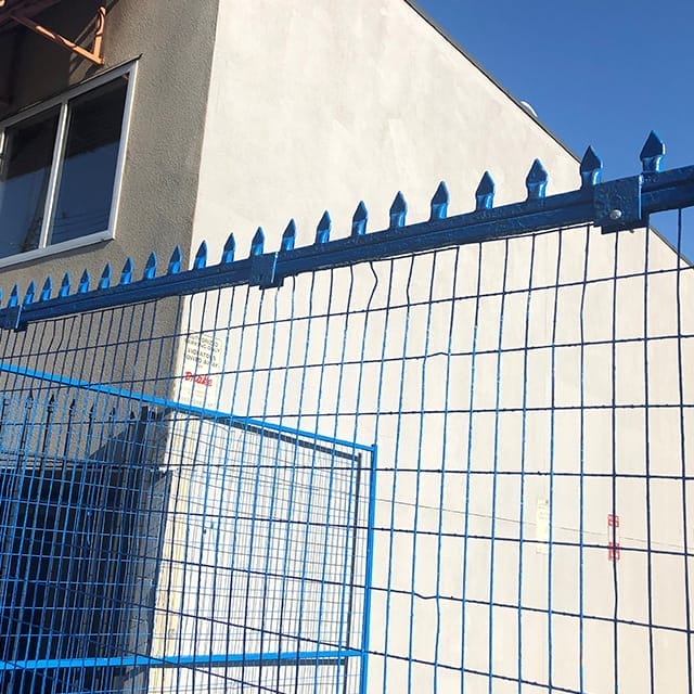 Blue metal spike rail used as a protective barrier or fencing