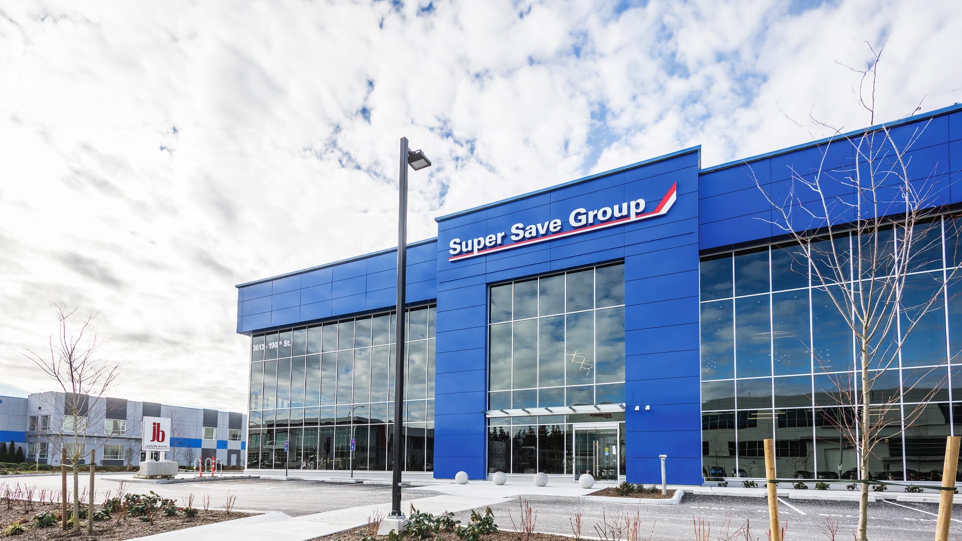 Exterior view of a modern building with glass windows and a blue facade, labelled "Super Save Group."