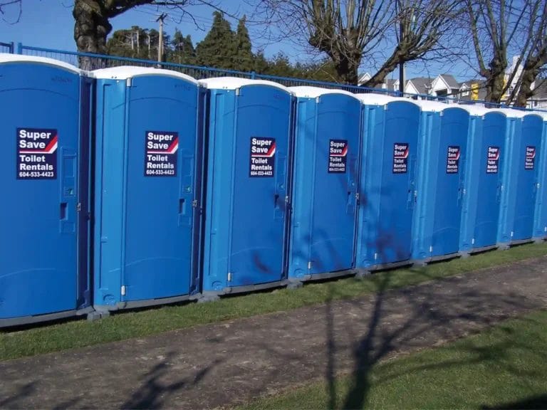 A row of blue portable toilets with "Super Save Toilet Rentals" signage in a grassy outdoor area