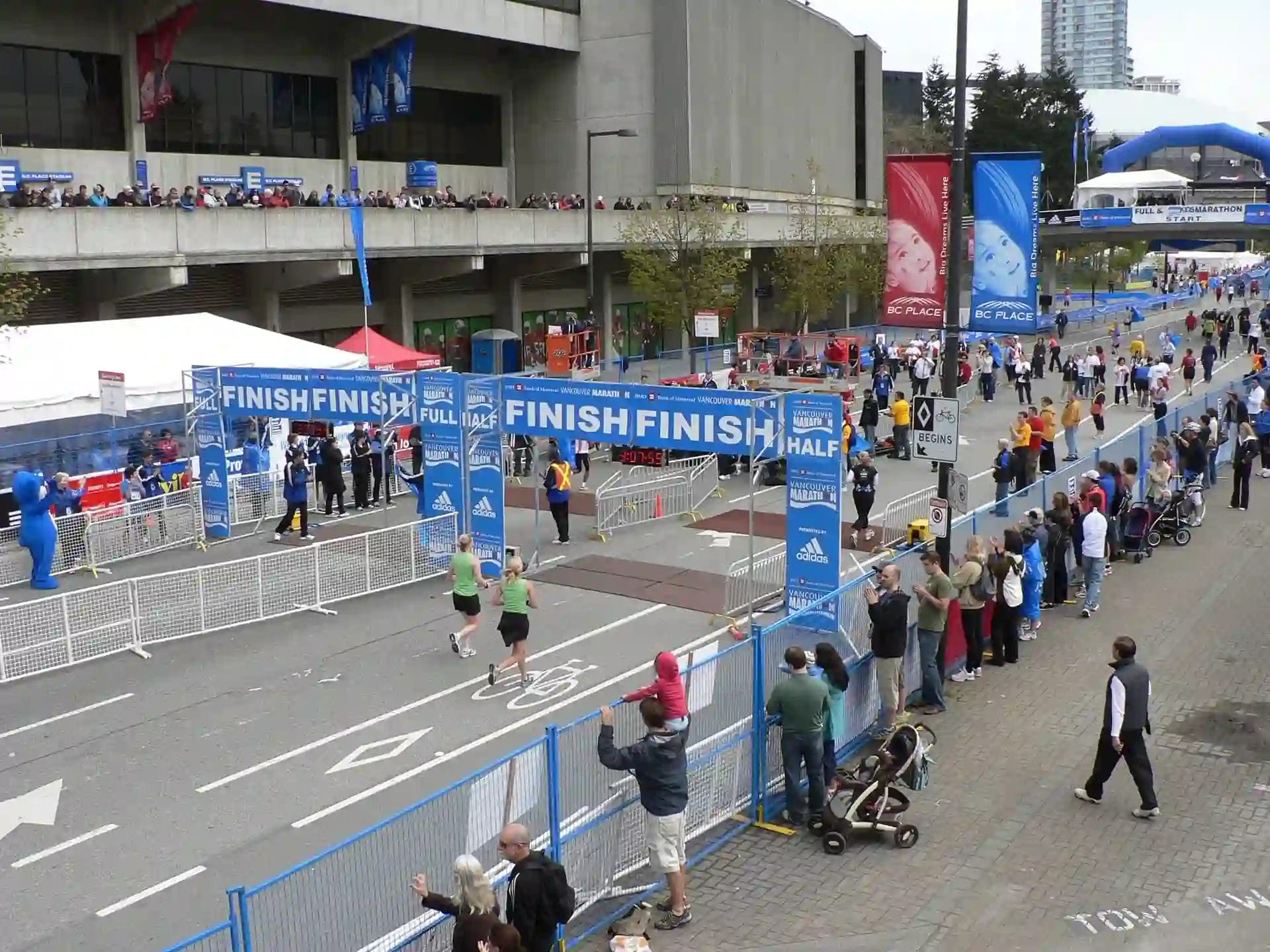 Runners crossing the finish line at the Vancouver Marathon with spectators cheering from both sides